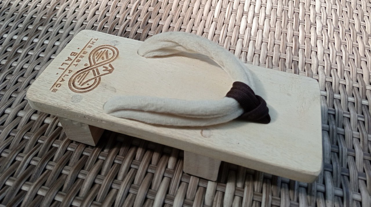 Side profile of the wooden geta showing the architectural silhouette and engraved logo